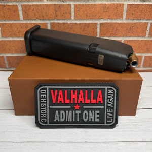 May include: A black and gray patch with the text "Valhalla - Admit One" in red. The patch has a star and the text "Die Historic" and "Live Again" on either side.