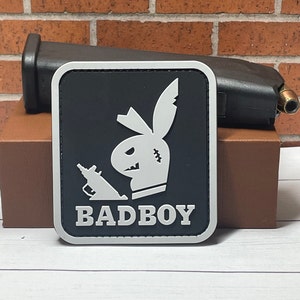 May include: Black and white patch with a cartoon bunny holding a gun and the text "BADBOY".