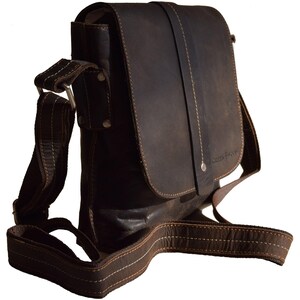 May include: A brown leather messenger bag with a flap closure and an adjustable shoulder strap. The bag has a small pocket on the front with the text "Wooden & Sons" embossed on it.