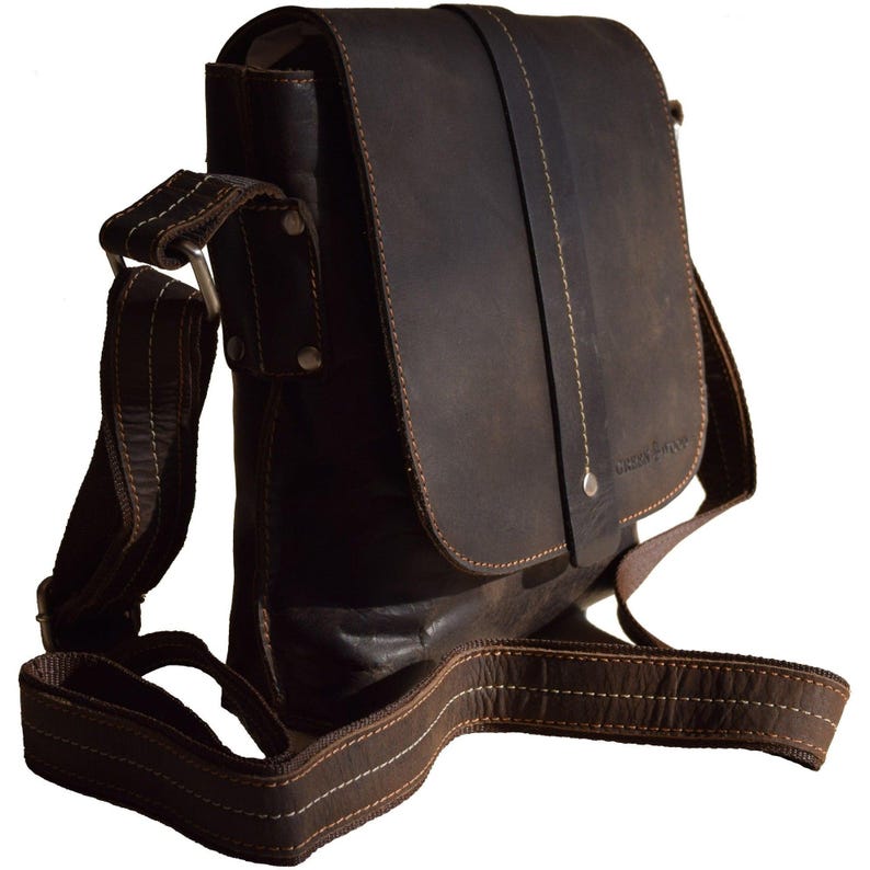 May include: A brown leather messenger bag with a flap closure and an adjustable shoulder strap. The bag has a small pocket on the front with the text "Wooden & Sons" embossed on it.
