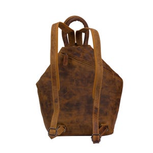 May include: A brown leather backpack with adjustable straps and a zip closure. The backpack has a distressed look and a unique triangular shape.