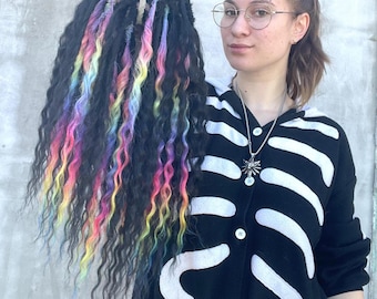 May include: A long, black wig with colorful streaks of pink, blue, yellow, and green. The wig is styled in loose, wavy dreadlocks.