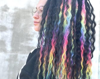 May include: A person with long, black, curly hair with rainbow colored streaks. The hair is pulled back into a ponytail.
