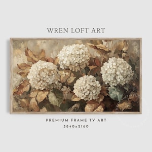 Op de afbeelding: Een schilderij van witte hortensia's met bruine en groene bladeren. Het schilderij is in een licht houten lijst.