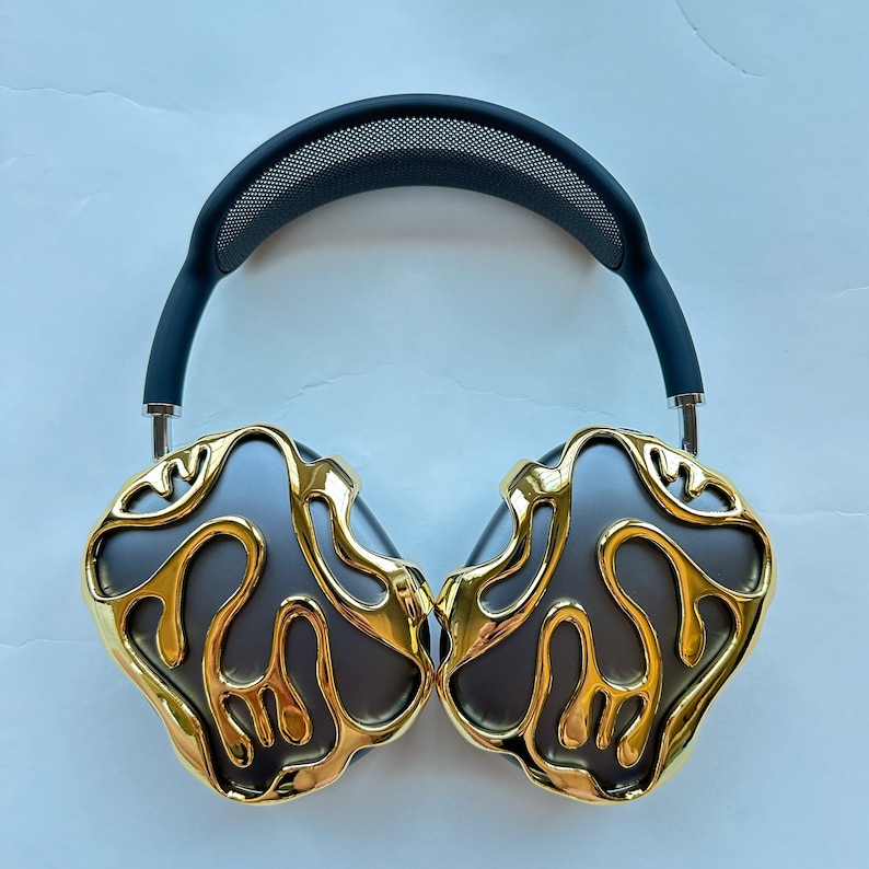 May include: Over-ear headphones with a black headband and gold-colored earcups. The earcups have a unique, organic design with a textured surface.
