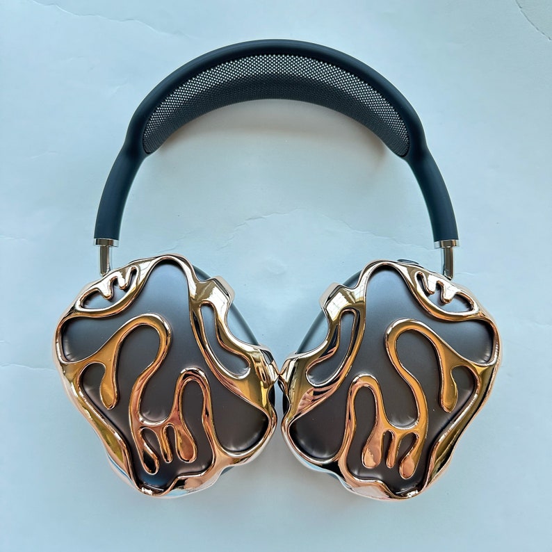 May include: A pair of black and gold headphones with a unique, abstract design. The headphones have a black headband and earcups with a gold, swirling pattern.