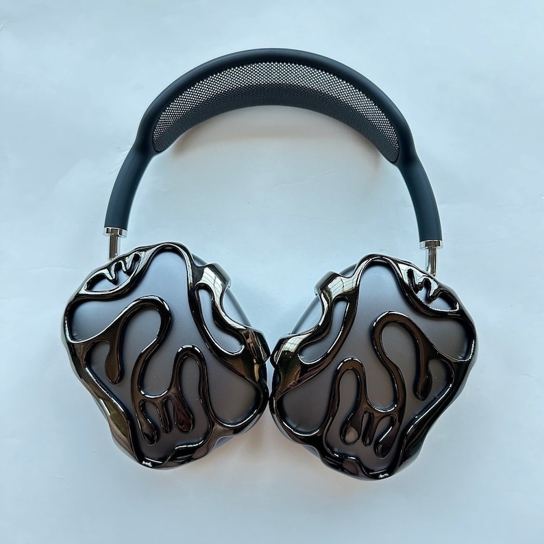 May include: Black headphones with a unique, abstract design on the earcups. The headphones have a black headband with a mesh pattern.