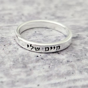 Peut inclure: Une bague en argent avec les mots hébreux "HaYom,  SheLi" gravés sur la bande.
