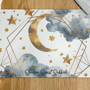 Peut inclure: Planche à découper rectangulaire en verre avec un motif céleste. Fond blanc avec étoiles dorées, croissant de lune et nuages aquarelle. L'inscription "Shalom Sweet Sukkah" est en écriture cursive. Un cadre géométrique doré entoure le motif.