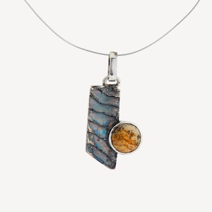 May include: A silver chain necklace with a pendant featuring a textured, blue and silver rectangular piece with a round, brown and white stone.