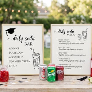 May include: A "dirty soda bar" setup with two framed signs, soda cans, and syrup bottles. One sign reads "dirty soda bar" with instructions. The other sign is a menu with drink options. The scene is set outdoors with a blurred background.