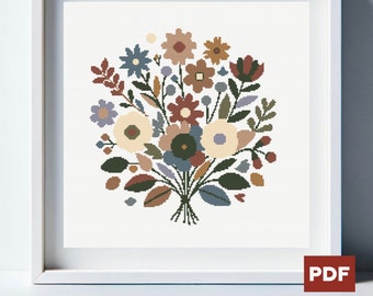 Könnte beinhalten: Ein gerahmtes Kreuzstich-Blumenbouquet in einem weißen Rahmen. Das Bouquet zeigt Blumen in Creme-, Braun-, Blau- und Grüntönen. Das Kunstwerk ist ein PDF-Download, wie durch das PDF-Symbol unten rechts angezeigt.