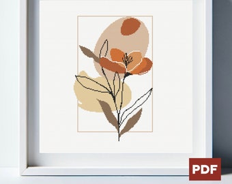 Op de afbeelding: Een kruissteekpatroon met een gestileerde bloem met oranje bloemblaadjes en bruine bladeren, tegen een achtergrond van abstracte vormen in beige en bruin.