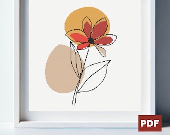 Op de afbeelding: Een digitaal kruissteekpatroon met een gestileerde bloem met rode en oranje bloemblaadjes, een bruine stengel en groene bladeren. De bloem wordt omringd door twee abstracte vormen, een gele en een bruine.