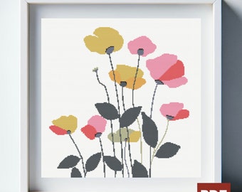 Op de afbeelding: Een ingelijst kruissteek bloemenkunstwerk. Het kunstwerk toont gestileerde bloemen in tinten geel, roze en rood met donkergrijze stelen en bladeren tegen een crèmekleurige achtergrond. De lijst is wit.
