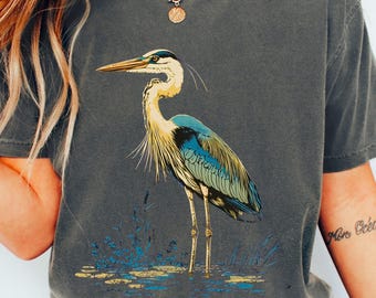 Camiseta vintage com garça-azul-grande, ideal para observação de pássaros, perfeita para amantes da natureza e arte folclórica.