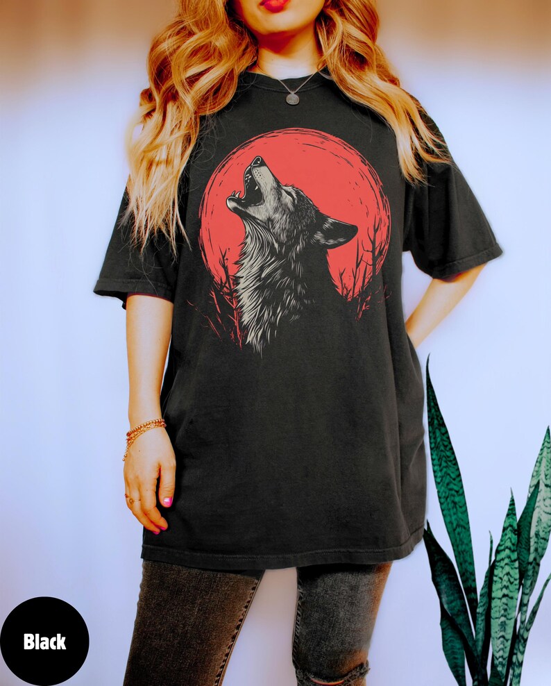 May include: A black t-shirt with a graphic of a wolf howling at a red moon. The wolf is in a black and white silhouette.