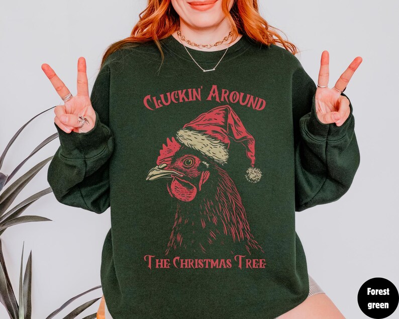 May include: A dark green sweatshirt with the text "Cluckin' Around The Christmas Tree" and a cartoon image of a rooster wearing a Santa hat.