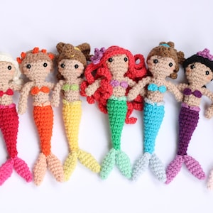 May include: A set of eight crocheted mermaid dolls with different colored tails. The mermaids are all wearing different colored tops and have different hairstyles.