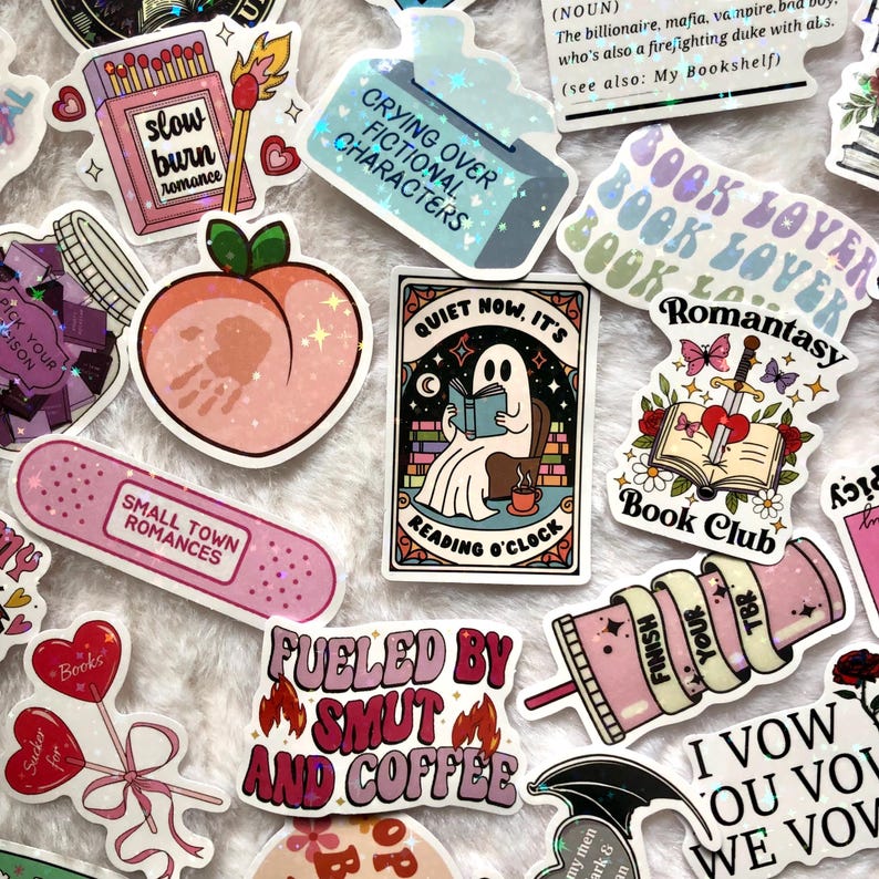 May include: A collection of colorful stickers with various designs and text. Stickers include a peach, a ghost reading a book, a matchbox with "slow burn romance", and a band-aid with "small town romances". Other stickers say "Crying Over Fictional Characters" and "Fueled by Smut and Coffee".