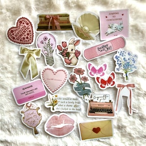 May include: A set of 15 pink and white aesthetic stickers featuring various designs, including a heart with the text "Hopeless Romantic", a lightbulb with flowers, a bunny holding flowers, a butterfly, a typewriter, and a ribbon. The stickers are perfect for adding a touch of whimsy to journals, laptops, water bottles, and more.