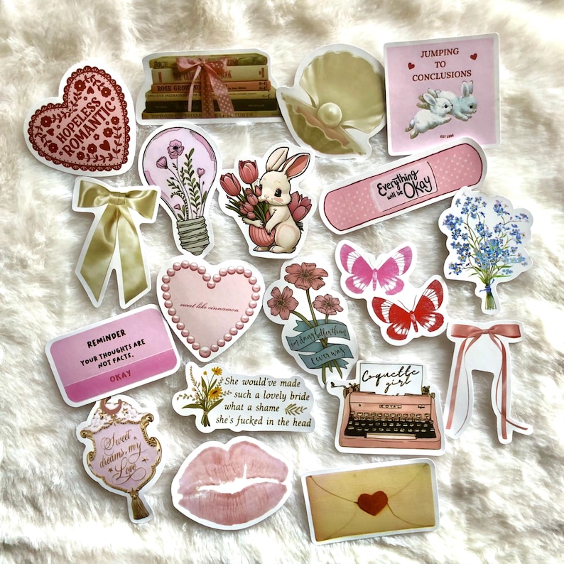 May include: A set of 15 pink and white aesthetic stickers featuring various designs, including a heart with the text "Hopeless Romantic", a lightbulb with flowers, a bunny holding flowers, a butterfly, a typewriter, and a ribbon. The stickers are perfect for adding a touch of whimsy to journals, laptops, water bottles, and more.