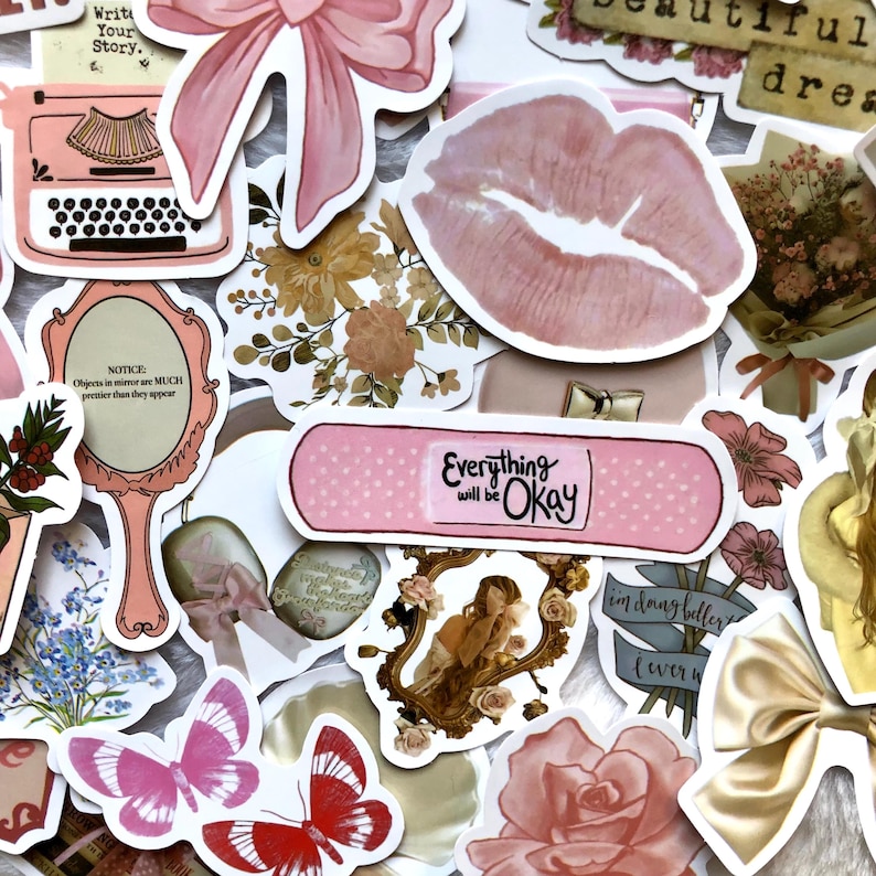 May include: A collection of pink and white stickers with various designs, including a typewriter, a mirror, a band-aid, a flower, a butterfly, a rose, and a lip print. The stickers have text that says "Write Your Story", "Notice: Objects in mirror are MUCH prettier than they appear", "Everything will be Okay", and "I'm doing better than ever".