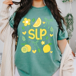 May include: Light green t-shirt with a lemon-themed design. The shirt features the letters "SLP" in yellow, along with lemon slices, flowers, and hearts. The words "Light Green" are printed at the bottom right.