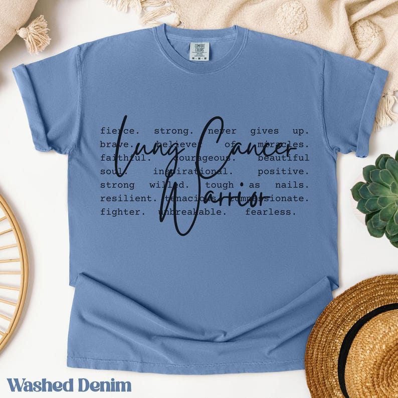 May include: A light blue t-shirt with a black graphic design that reads "Cancer.  Fierce. Strong. Never gives up. Brave. Believe in miracles. Faithful. Courageous. Beautiful soul. Inspirational. Positive. Strong willed. Tough as nails. Resilient. Tenacious. Passionate. Fighter. Unbreakable. Fearless."