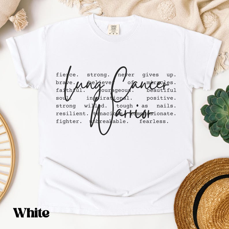 May include: White t-shirt with a black graphic design that reads "Cancer Warrior" and defines the word with positive attributes like "strong", "brave", "resilient", and "unbreakable".
