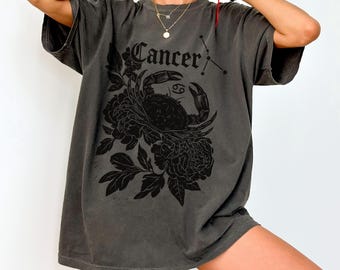 Op de afbeelding: Donkergrijs T-shirt met een zwarte afbeelding van een krab, bloemen en het woord "Cancer" met het sterrenbeeld Kreeft. Het shirt heeft een relaxte pasvorm en korte mouwen. Het woord "Pepper" staat linksonder gedrukt.