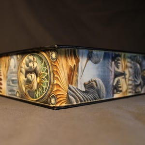 Op de afbeelding: Een gesloten doos met een kleurrijk, ge&iuml;llustreerd ontwerp met verschillende figuren en patronen. De doos is gemaakt van karton en heeft een zwarte rand.