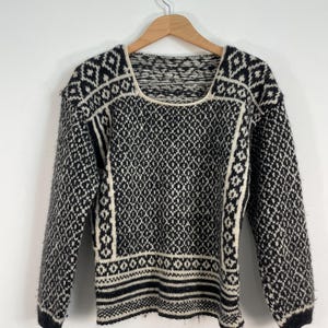 Könnte beinhalten: Schwarz-weißer Pullover mit quadratischem Ausschnitt. Der Pullover ist aus weichem, flauschigem Material.