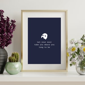May include: A framed print with a navy blue background and white text that reads "let your soul take you where you long to be". A white phantom mask is centered above the text.