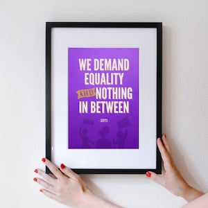 May include: A framed print with a purple background and white text that reads "We demand equality and nothing in between - SUFFS -" with a silhouette of three people holding signs.