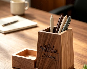 May include: A wooden desk organizer with a tall pen holder section and a shallow tray. The front of the pen holder features a black graphic of botanical sprigs above the name Eileen in script text. Four pens are stored inside the holder.