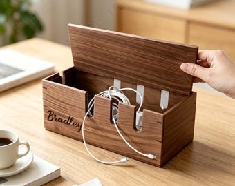 May include: A rectangular dark wood cable management box with a hinged lid. The front panel features the name Bradley engraved in script. The box has three vertical cutouts for cables and internal white hooks for organizing charging cords.