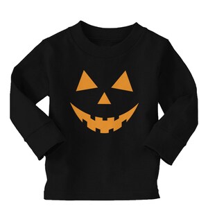 Puede incluir: Camiseta negra de manga larga con un gráfico de cara de calabaza naranja.