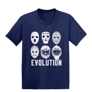 May include: A navy blue t-shirt with a white graphic of hockey goalie masks, showing the evolution of the mask design. The text "EVOLUTION" is printed below the masks.