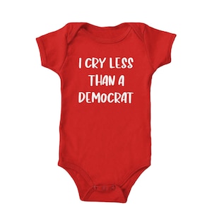 Puede incluir: Un body de bebé rojo con texto blanco que dice "Lloro menos que un demócrata".