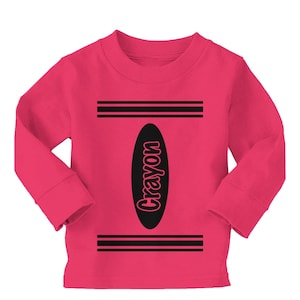 May include: Pink long-sleeved shirt with a black crayon design. The design includes the word "Crayon" written vertically.