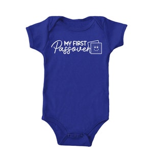 May include: A royal blue baby onesie with white text that reads "My First Passover" and a white graphic of a matzah cracker with a smiley face.