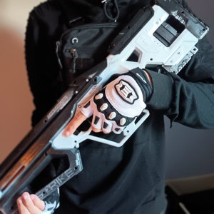 May include: A white and black tactical-style glove with a black wrist strap and the word "Gripforce" printed on the strap. The glove has a white mesh fabric and black rubberized fingertip protection.