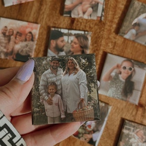 Könnte beinhalten: Ein Satz quadratischer Fotomagnete mit einer vierköpfigen Familie. Die Magnete sind in einem Raster auf einer Holzoberfläche angeordnet. Die Fotos zeigen ein Paar mit ihren beiden Kindern. Die Fotos sind im Vintage-Stil mit einer warmen Farbpalette gehalten.