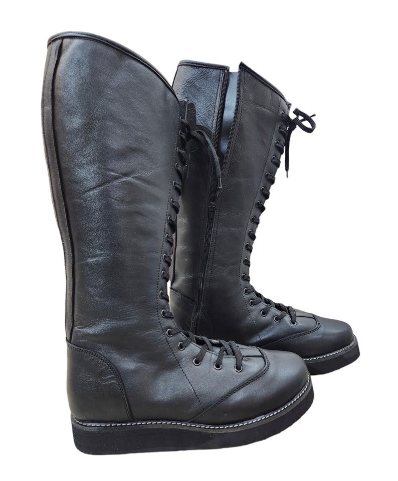 May include: A pair of black leather wrestling boots with laces and a zipper on the side.