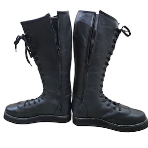 May include: A pair of black leather wrestling boots with laces and a zipper on the side.