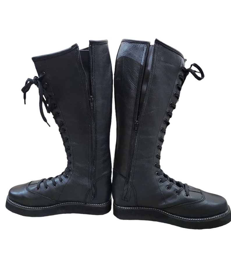May include: A pair of black leather wrestling boots with laces and a zipper on the side.