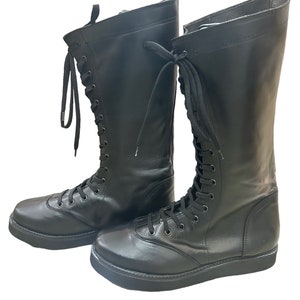Puede incluir: Un par de botas negras de cuero con cordones y suela de plataforma gruesa.