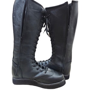 May include: A pair of black leather wrestling boots with laces up the front and a zipper on the side. The boots have a thick platform sole.