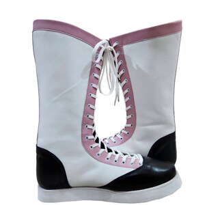 May include: A pair of white wrestling boots with black and pink accents. The boots have laces up the front and a thick white sole.